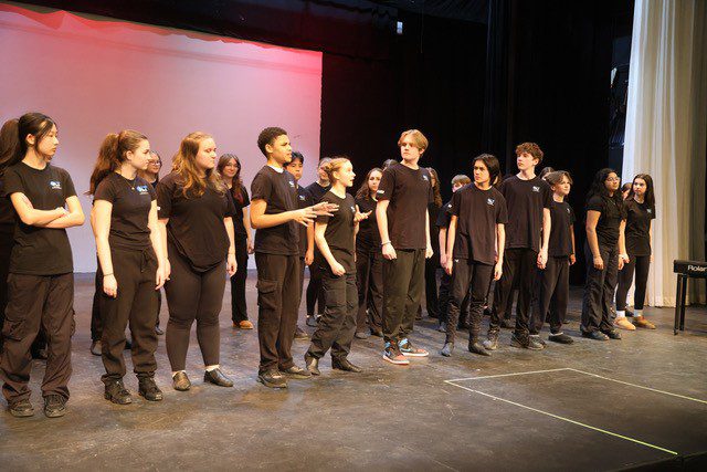 Young performers from the Oshawa Little Theatre Youth Group rehearse a scene from Disney’s Newsies on stage.